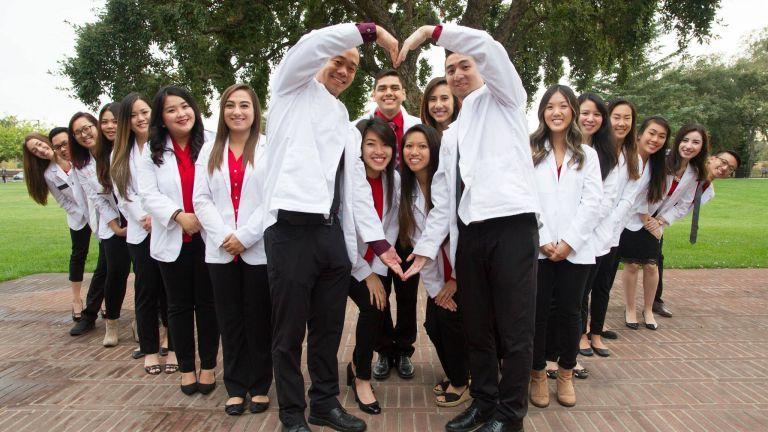 Pharmacy students forming heart shape with arms.